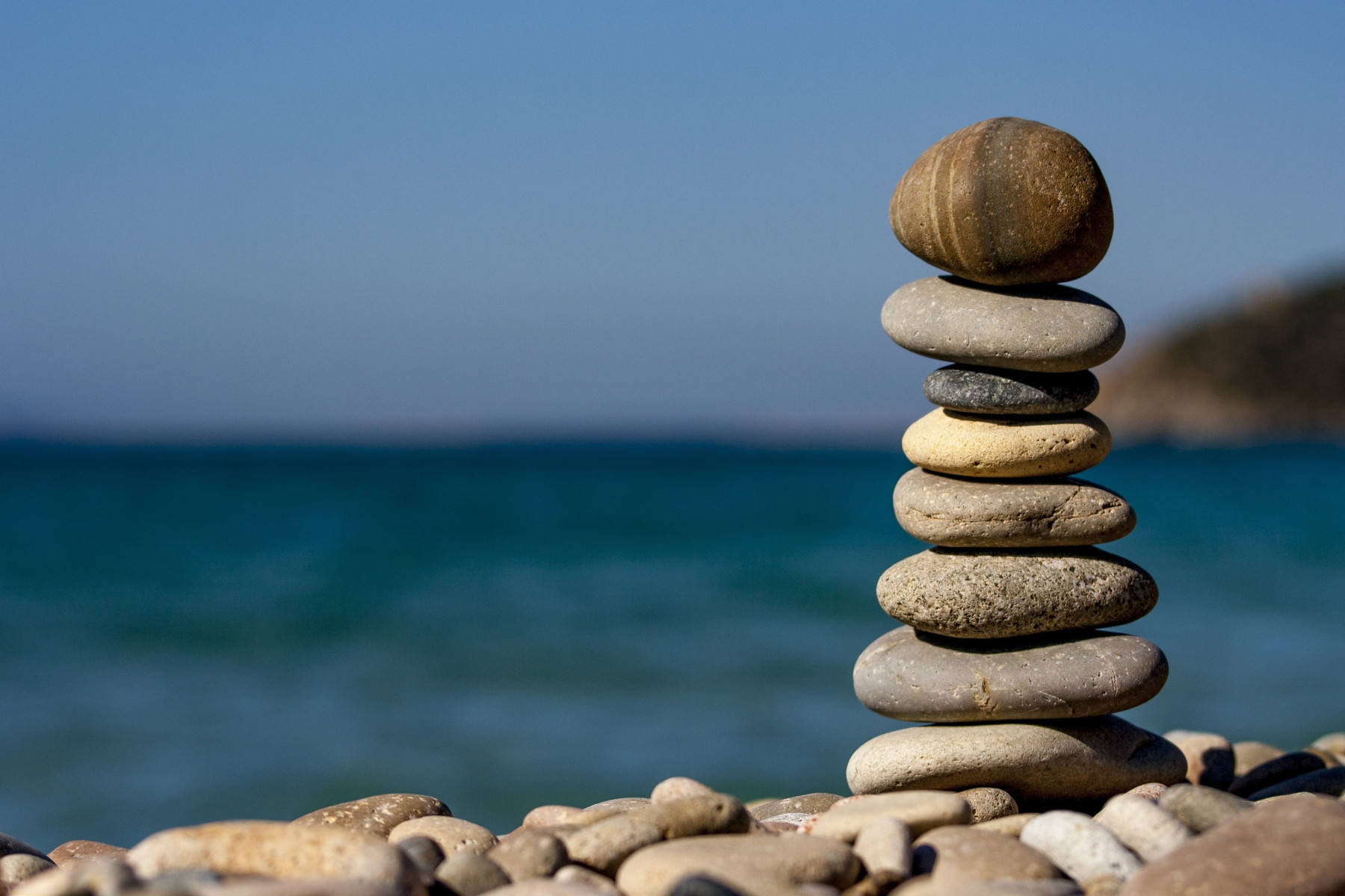 image of a shore focused on rocks piled over each other with the sea on the background